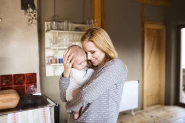 Smiling mother holding baby at home - HAPF01398