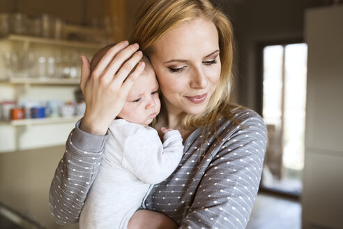 Lächelnde Mutter hält Baby zu Hause - HAPF01400