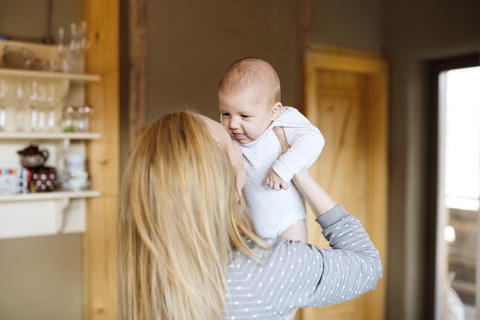 Mutter hebt Baby zu Hause hoch, lizenzfreies Stockfoto