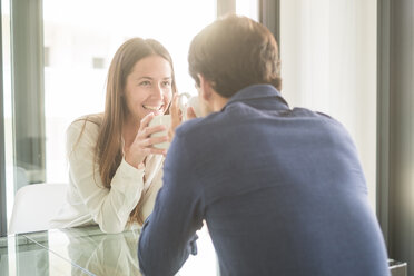 Happy young couple sitting at table with coffee cups - SIPF01526