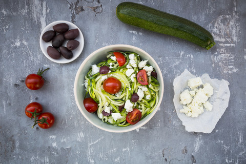 Schüssel mit Zucchini-Spaghetti mit Feta, Kirschtomaten und schwarzen Oliven, lizenzfreies Stockfoto