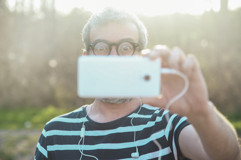 Starring man taking picture of viewer with smartphone stock photo