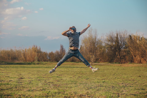 Mann springt in die Luft, während er ein Foto mit einer alten Kamera macht, lizenzfreies Stockfoto