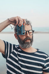 Portrait of bearded man taking photo of viewer with vintage camera - RTBF00803