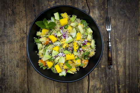 Schüssel mit Quinoa-Salat mit Mango, Avocado, Tomaten, Gurken, Kräutern und schwarzem Sesam, lizenzfreies Stockfoto