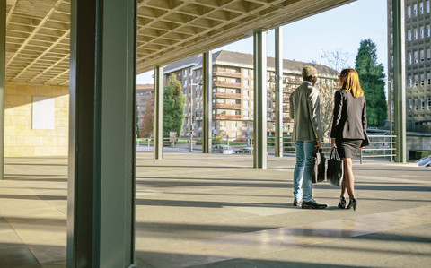 Junger Geschäftsmann und Frau unterhalten sich vor einem Bürogebäude, lizenzfreies Stockfoto