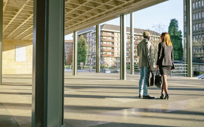 Junger Geschäftsmann und Frau unterhalten sich vor einem Bürogebäude - DAPF00628