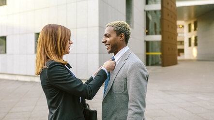 Young businesswoman fastening tie of young businessman - DAPF00631