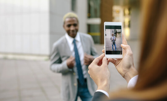 Junger Geschäftsmann und Frau fotografieren mit ihrem Smartphone - DAPF00633