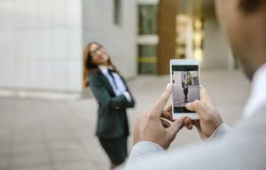 Junger Geschäftsmann und Frau fotografieren mit ihrem Smartphone - DAPF00634