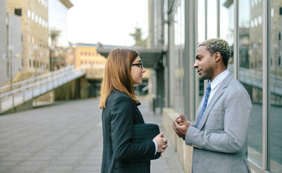 Junger Geschäftsmann und Frau im Gespräch vor einem Bürogebäude - DAPF00654