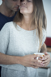 Junger Mann umarmt Freundin mit Kaffeetasse - SIPF01546