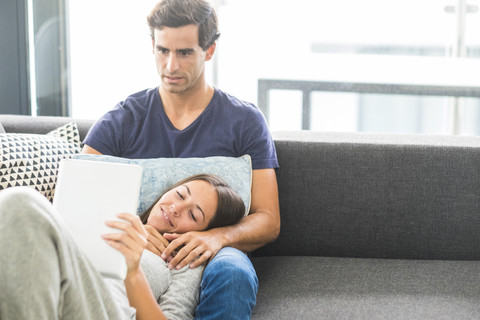 Junges Paar mit Tablet entspannt sich zu Hause, lizenzfreies Stockfoto