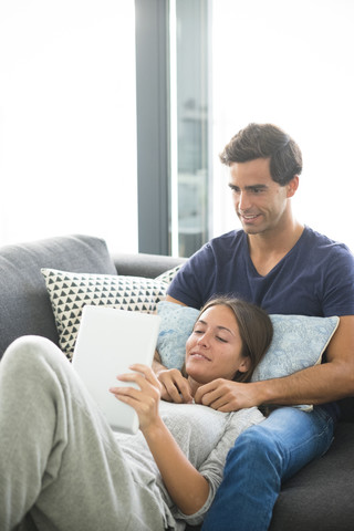 Junges Paar mit Tablet entspannt sich zu Hause, lizenzfreies Stockfoto