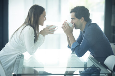 Glückliches junges Paar sitzt am Tisch mit Kaffeetassen - SIPF01569