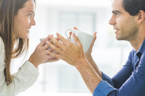 Junges verliebtes Paar hält Kaffeetassen, lizenzfreies Stockfoto