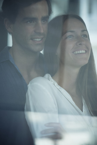 Smiling young couple looking out of window stock photo
