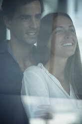 Smiling young couple looking out of window - SIPF01573