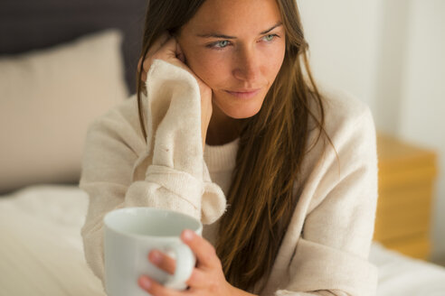 Junge Frau auf dem Bett sitzend mit einer Tasse Kaffee - SIPF01588