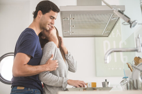 Glückliches, verliebtes junges Paar mit Kaffeetassen in der Küche - SIPF01600