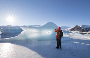Iceland, tourist taking cell phone picture of glacial ice - RAEF01796