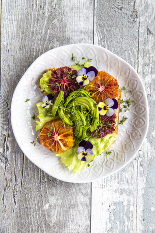 Toast garnished with iceberg salad, avocado, sliced blood orange, cress and horned violets stock photo