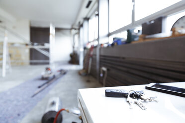 Keys and smartphone on table top at construction site - REAF00238