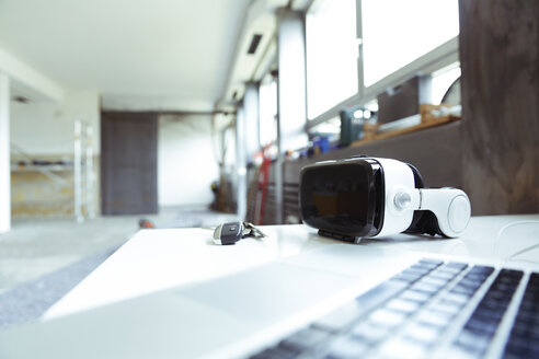 Laptop, Schlüssel und Virtual-Reality-Brille auf einer Tischplatte auf einer Baustelle - REAF00239