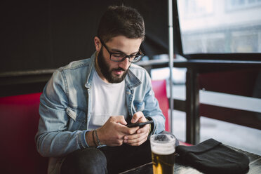 Young man text messaging in a pub - RAEF01808
