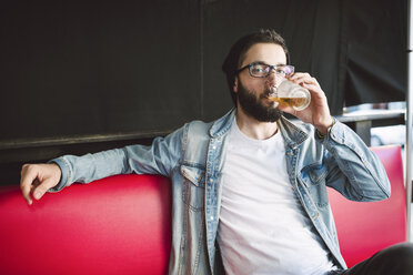 Junger Mann trinkt ein Glas Bier in einer Kneipe - RAEF01818