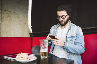 Young man sitting in a pub checking messages - RAEF01819