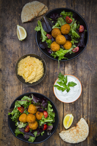 Schüsseln mit gemischtem Salat, Tomaten, süßer Kartoffel Falafel und Hummus, Joghurtsauce und Fladenbrot, lizenzfreies Stockfoto