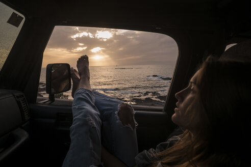Frau im Auto sitzend bei Sonnenuntergang - SIPF01618