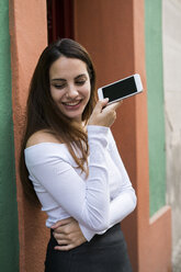 Portrait of smiling young woman with cell phone - KKAF00648