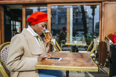 Junge Frau in Paris trinkt Bier in einem Café und liest Nachrichten - KIJF01360