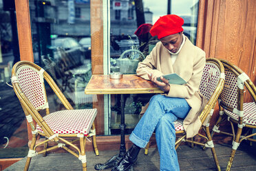 Junge Frau in Paris liest Speisekarte in einem Café - KIJF01366