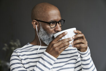 Mature man with earphones drinking coffee - FMKF03747