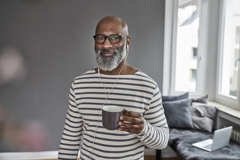 Mature man with earphones drinking coffee stock photo