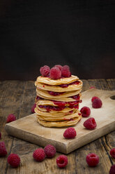 Stack of pancakes with raspberries and raspberry jam on wooden board - LVF06016