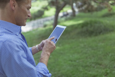 Mann benutzt Mini-Tablet in einem Park - BOYF00770