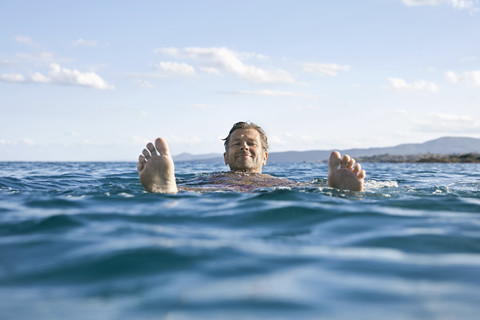 Entspannter reifer Mann schwimmt im Meer, lizenzfreies Stockfoto