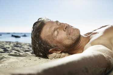 Portrait of man relaxing on sandy beach - PDF01089