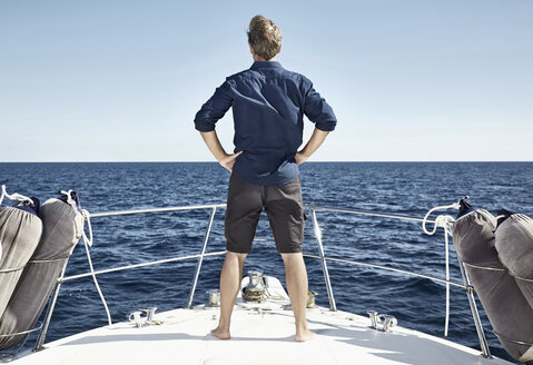 Back view of mature man standing on his motor yacht with hands on hips - PDF01113