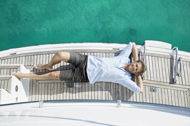 Smiling man lying on deck of his motor yacht - PDF01116
