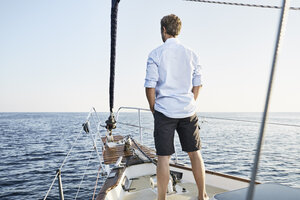 Rückenansicht eines reifen Mannes, der auf seinem Segelboot steht und in die Ferne schaut - PDF01155