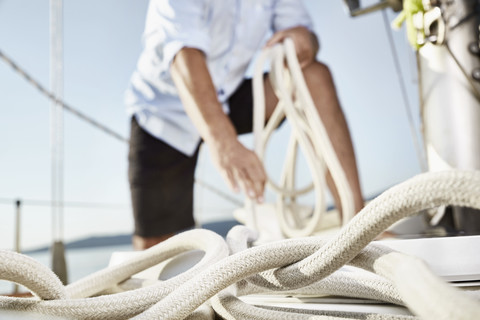 Rope on sailing boat with man working in the background stock photo