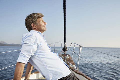 Älterer Mann entspannt sich auf seinem Segelboot, lizenzfreies Stockfoto