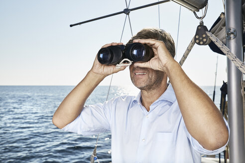 Älterer Mann mit Fernglas auf seinem Segelboot - PDF01179