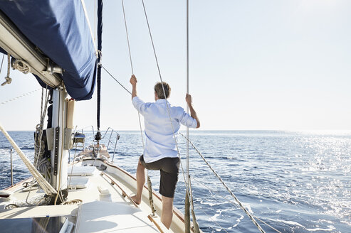 Back view of mature man standing on his sailing boat looking at distance - PDF01184