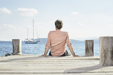 Back view of man sitting on jetty looking at distance - PDF01204